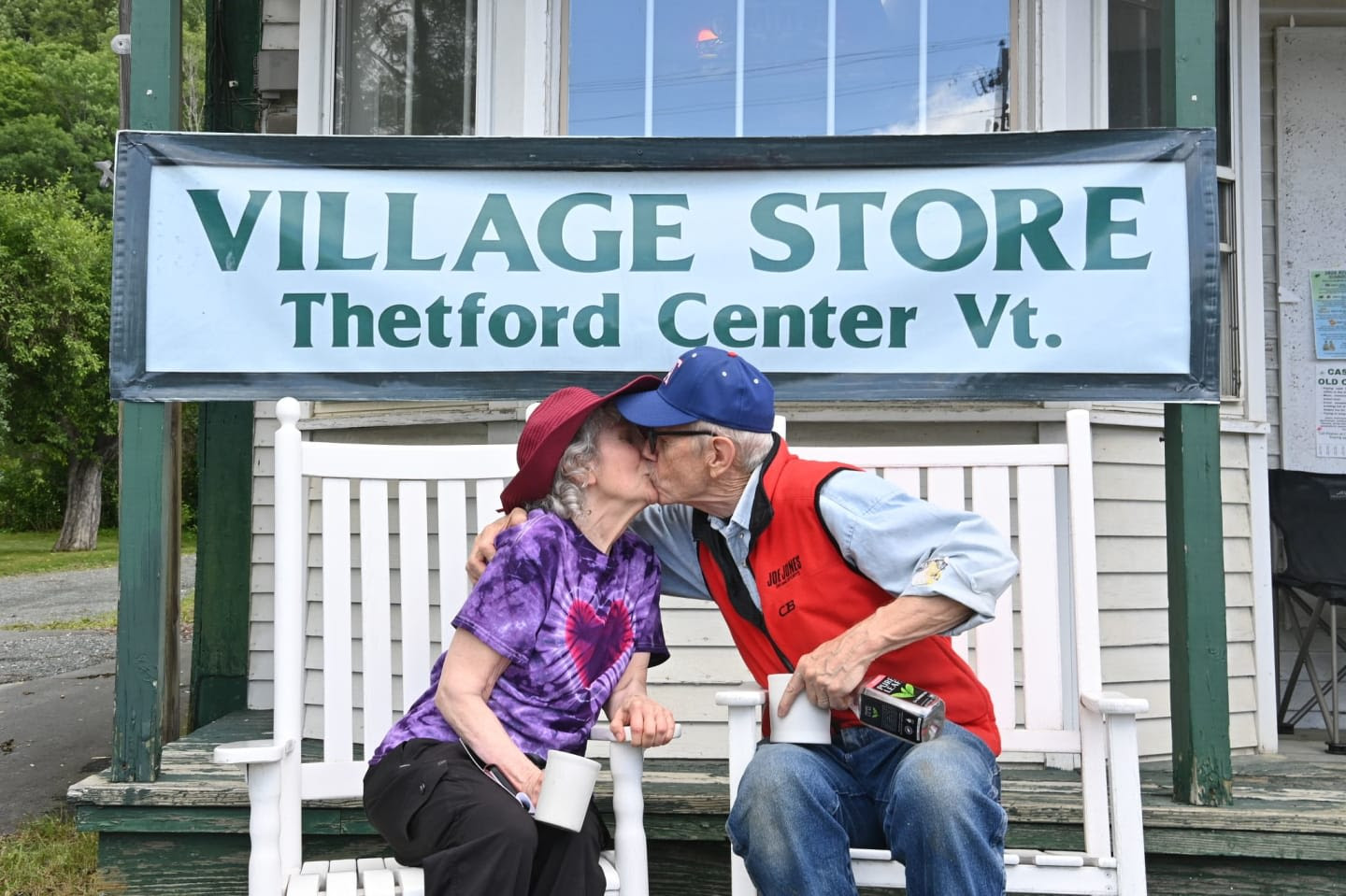 An older couple share a kiss beneath the Village Store, Thetford Center Vt. sign