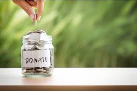 A glass jar labeled “Donate,” filling with coins